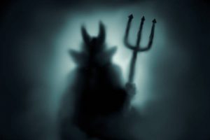 Creepy Devil silhouette behind a frozen glass and in the mist with backlit.
